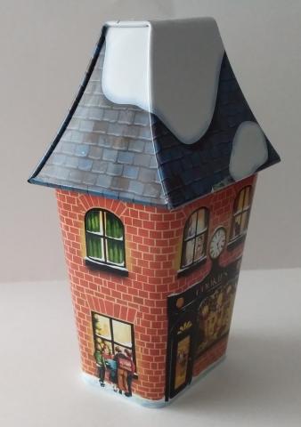 Lata de biscoitos de manteiga; Casinha de 1.º andar, neve no telhado; laterais paredes de tijolo c/ cenas do quotidiano; 7,5cmx 5,5cmx 19cm.